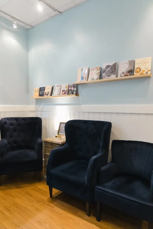 Meditation room with navy velvet armchairs and a shelf of books against pale blue walls
